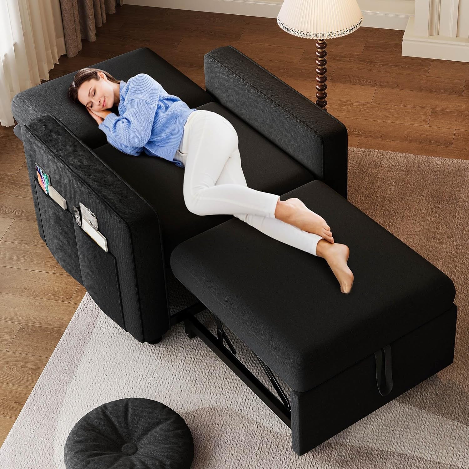 Black convertible chair pulled out into sleeper with person lying on it, angled top view
