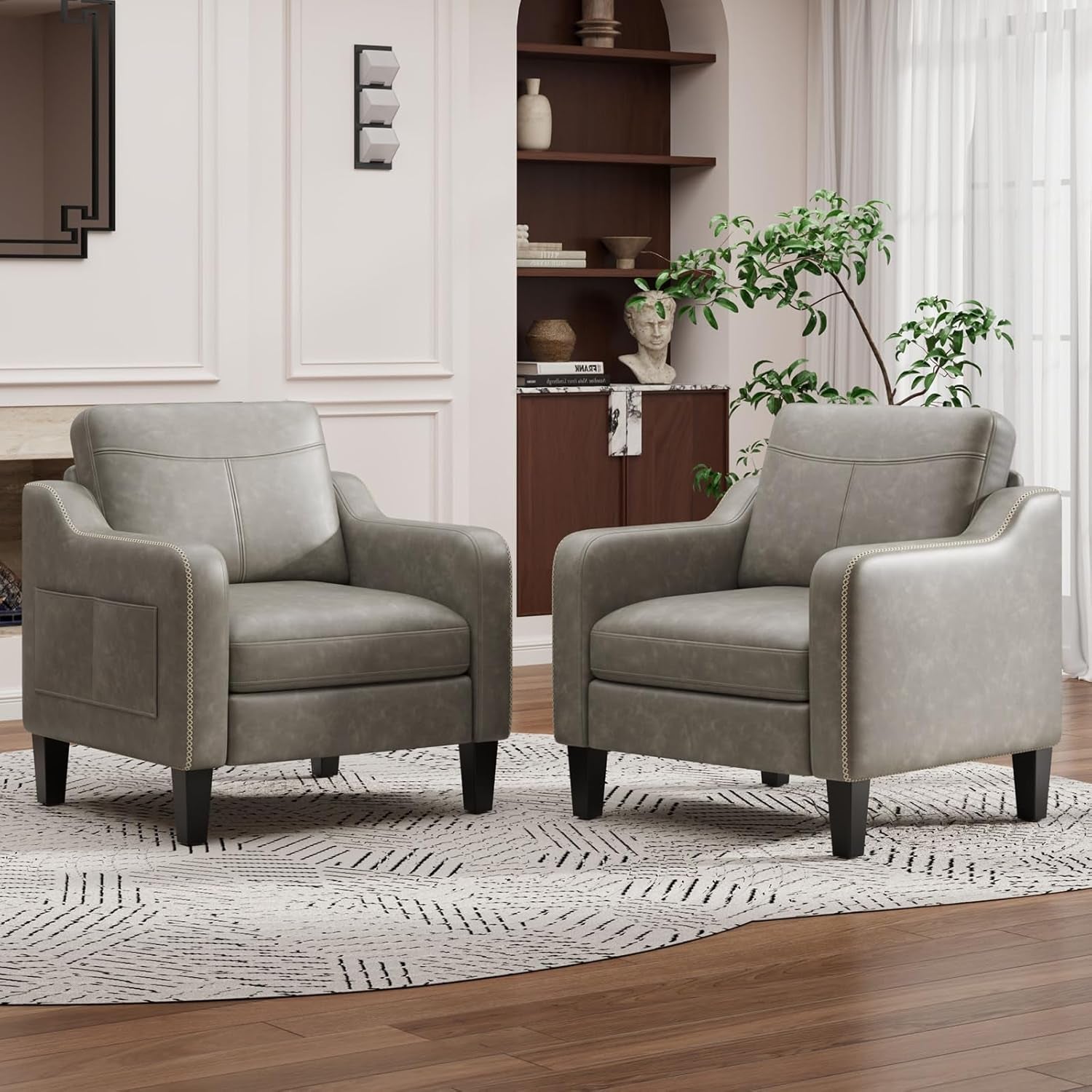 Pair of light gray PU leather armchairs shown side by side on a rug with shelving behind.