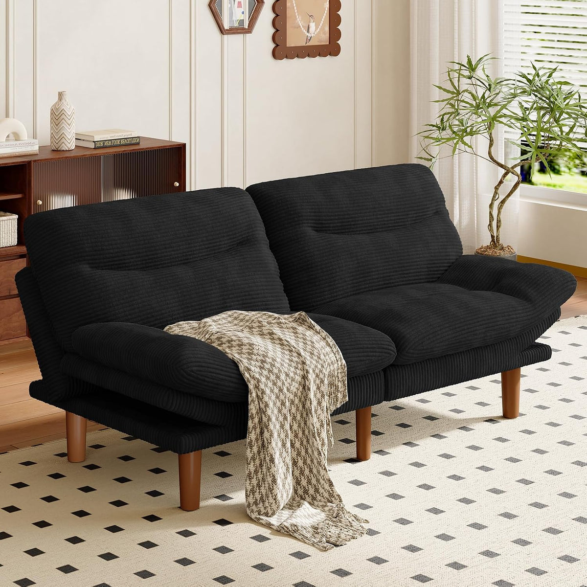 Black corduroy futon sofa shown in a styled room with a patterned throw draped front