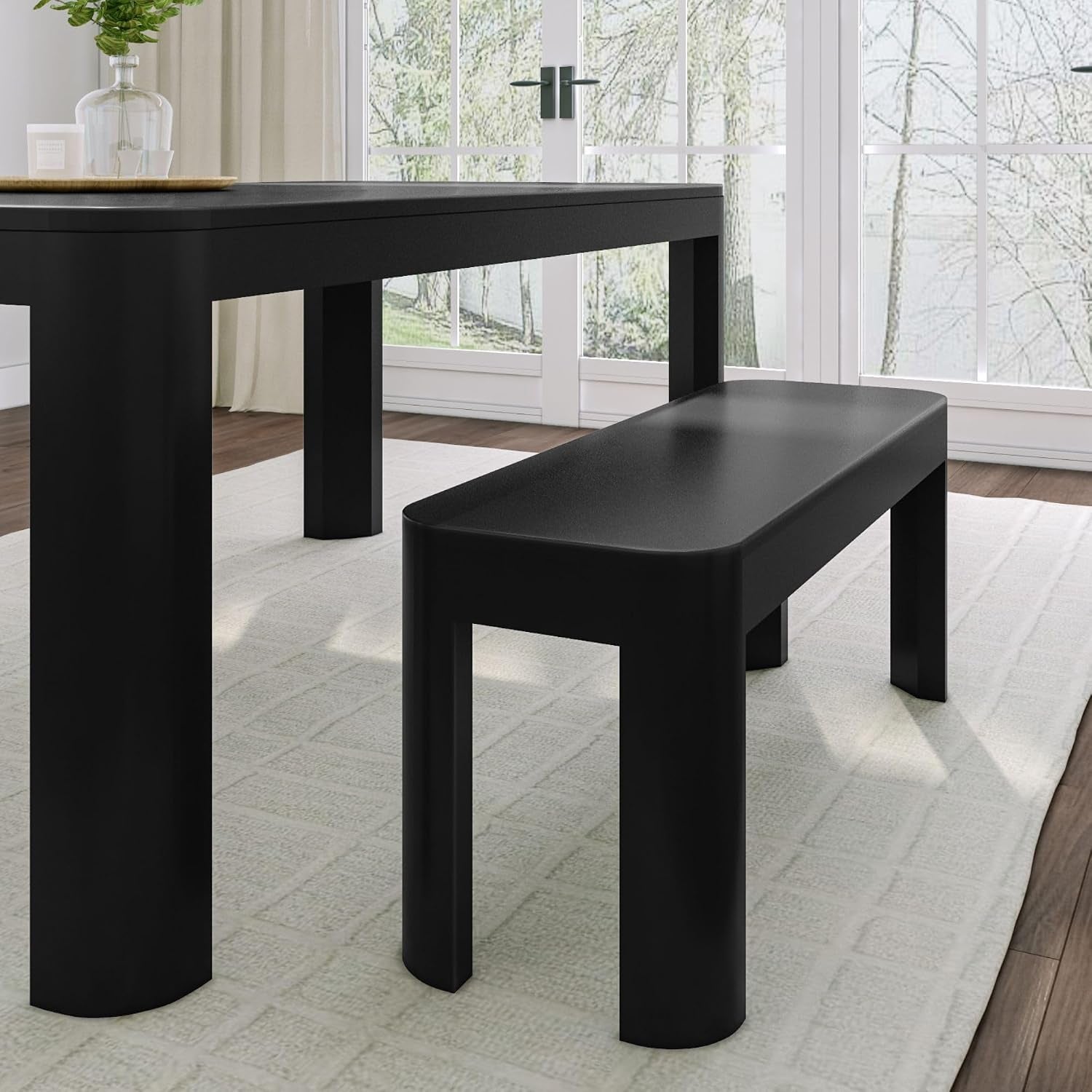 Side view of a black bench with rounded ends placed beside a matching table leg on a rug.