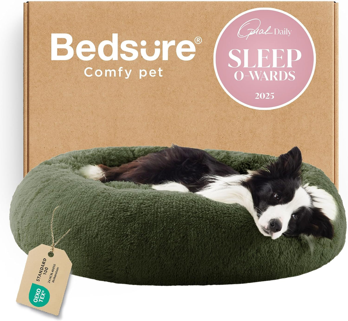 Front-facing view of a forest-green round faux-fur donut bed with a black-and-white dog resting and a cardboard box behind