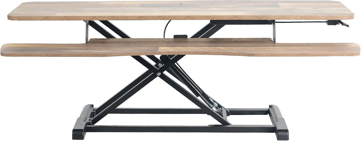 Side elevation of a standing desk converter with mixed wood top and black metal scissor base