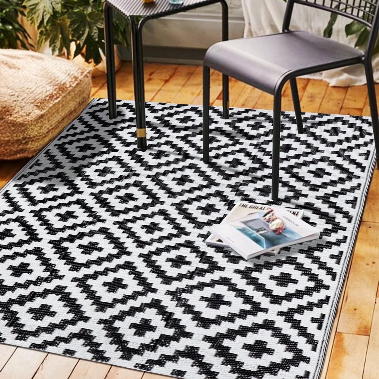 Indoor scene showing a black-and-white geometric outdoor rug under a chair and small table.