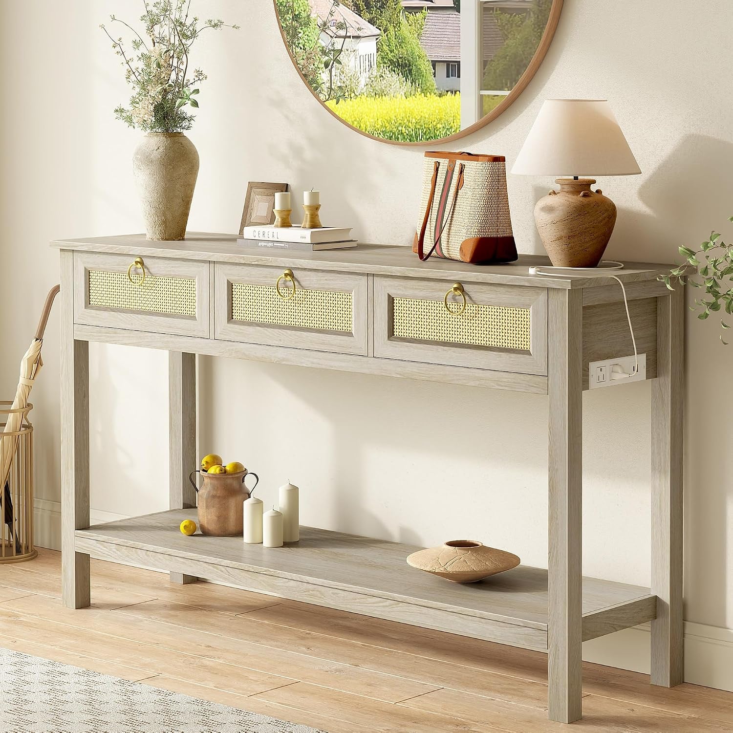 Light gray console table with three rattan-front drawers styled under a round mirror in a bright room.