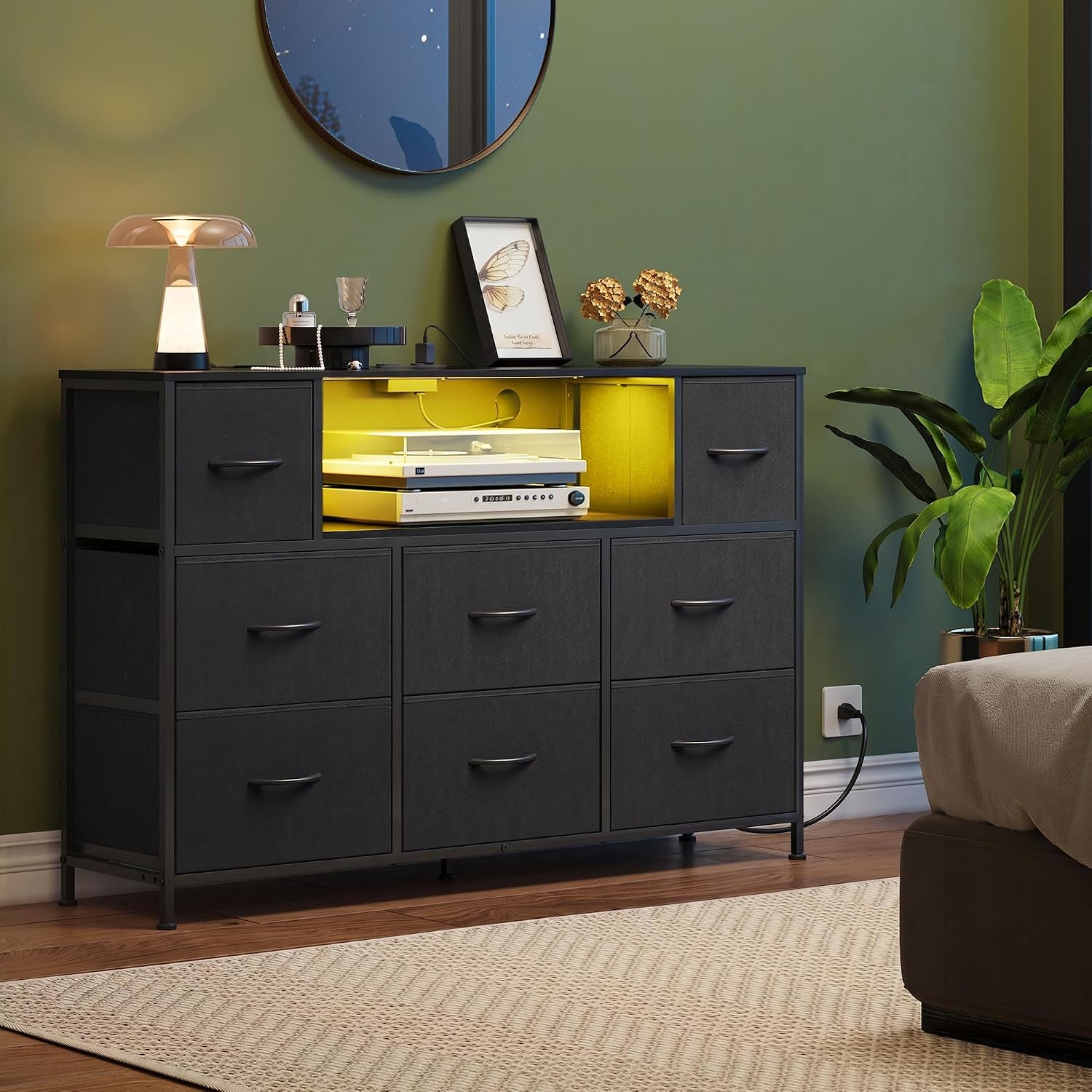 Black eight-drawer dresser in a styled bedroom with illuminated center cubby and decor on top.