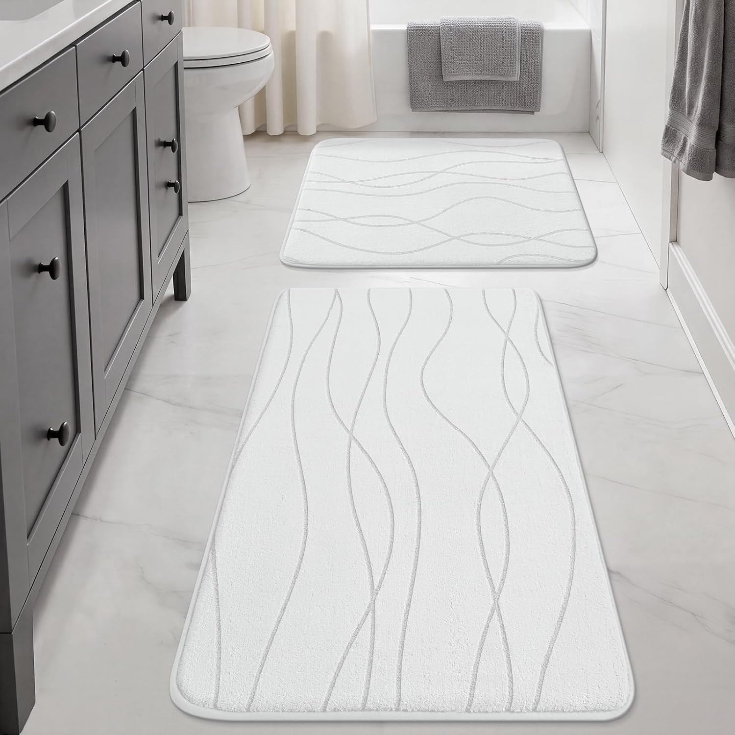 Bright bathroom view with a long white runner leading to a square white mat by the tub.