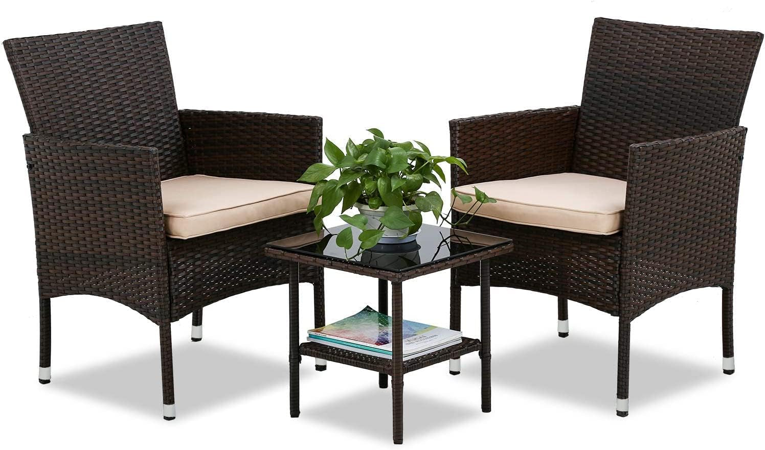 Pair of dark brown rattan chairs with beige cushions and a small glass-top side table with plant