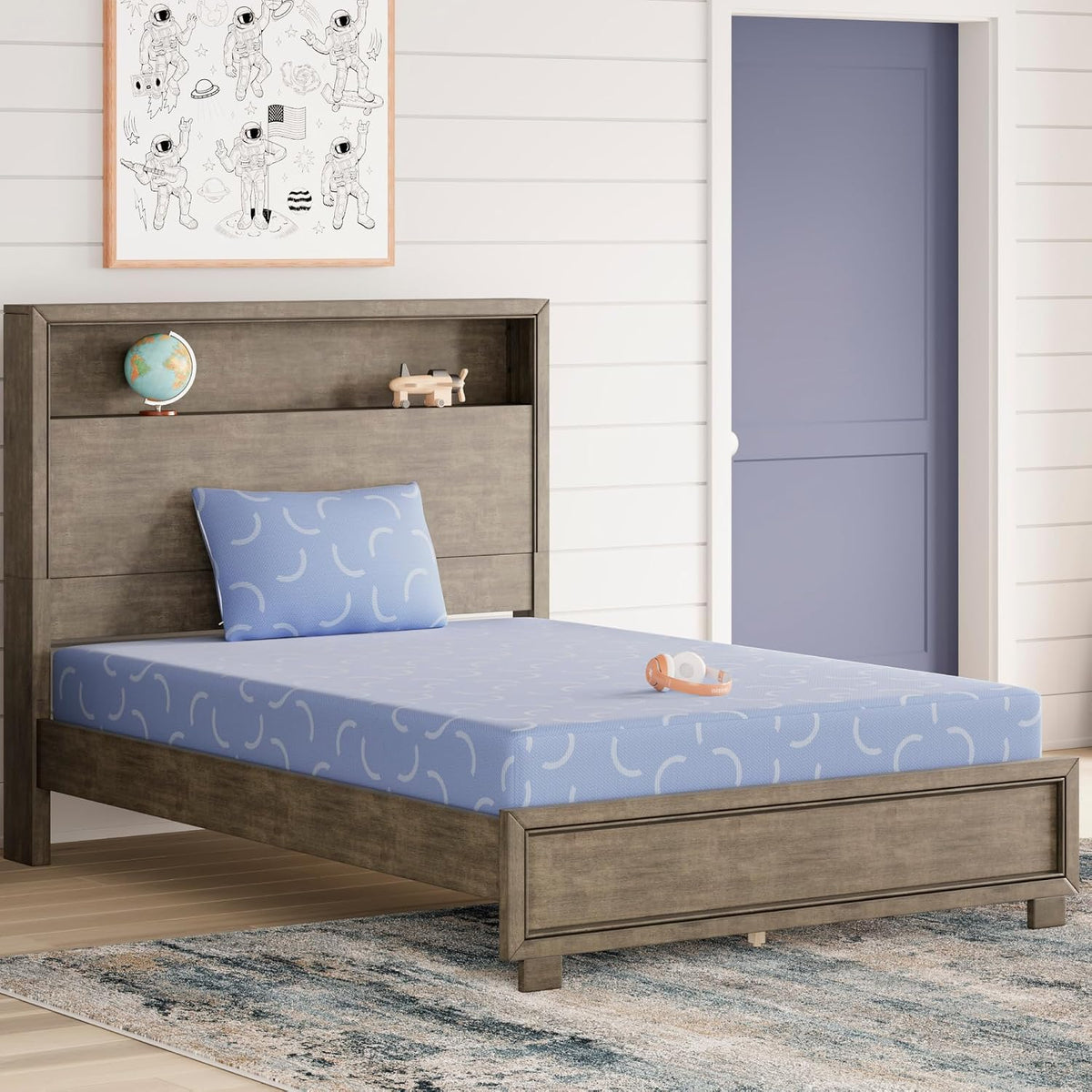 Gray wood bed with a blue patterned mattress and matching pillow, headphones on mattress, globe and toy plane on headboard