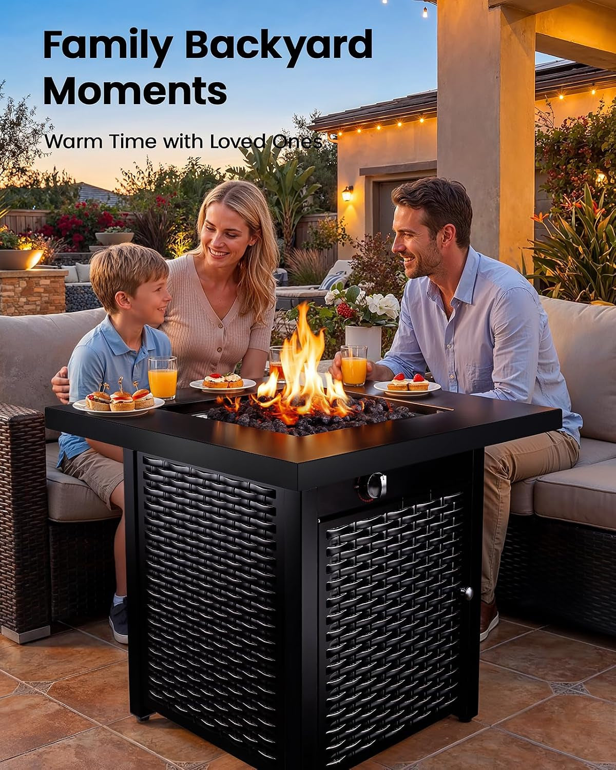 Family of three smiling around a lit square fire pit table on a patio, enjoying food and drinks at sunset.