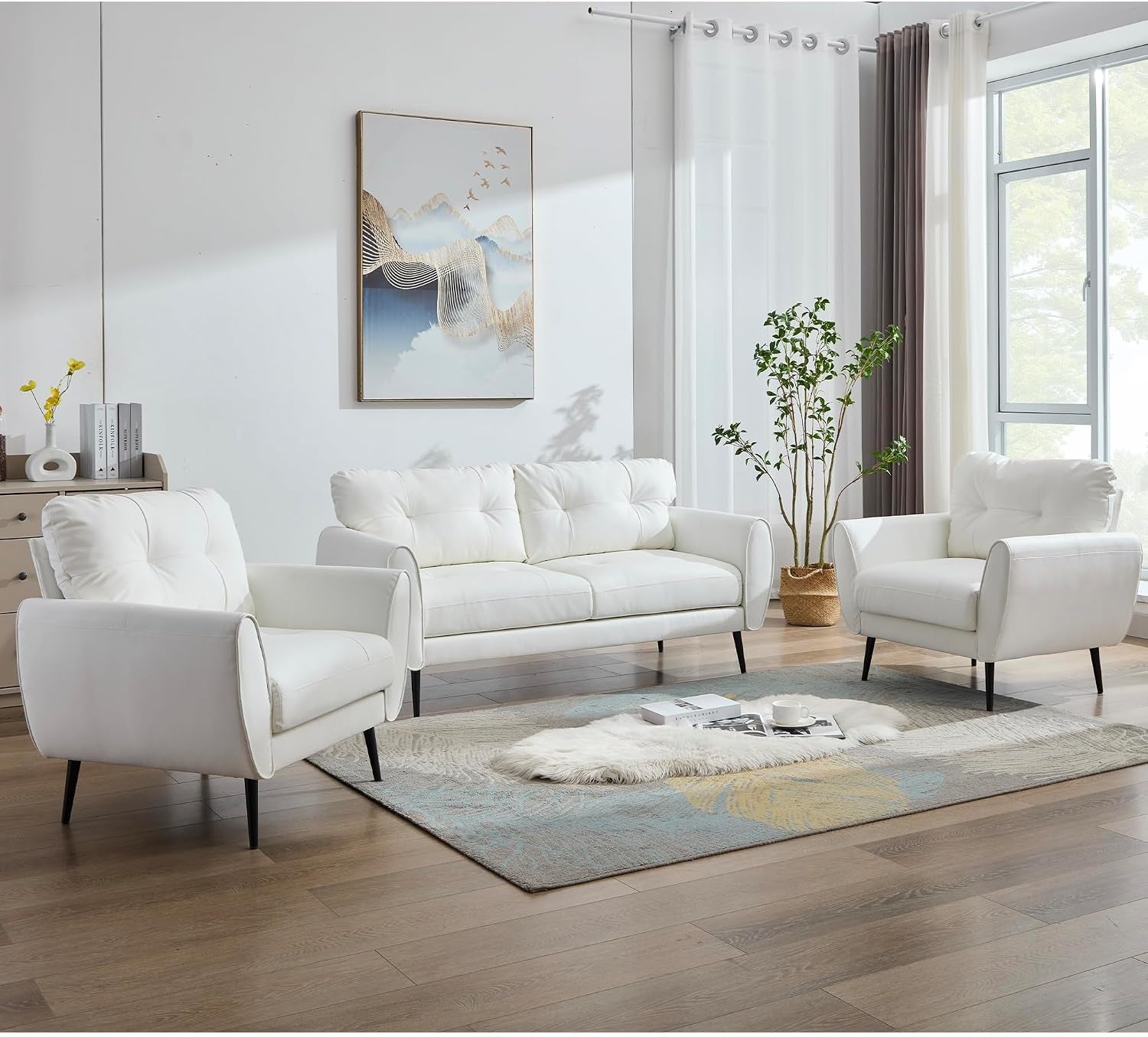 White tufted faux leather loveseat flanked by two matching armchairs angled front view in a bright living room