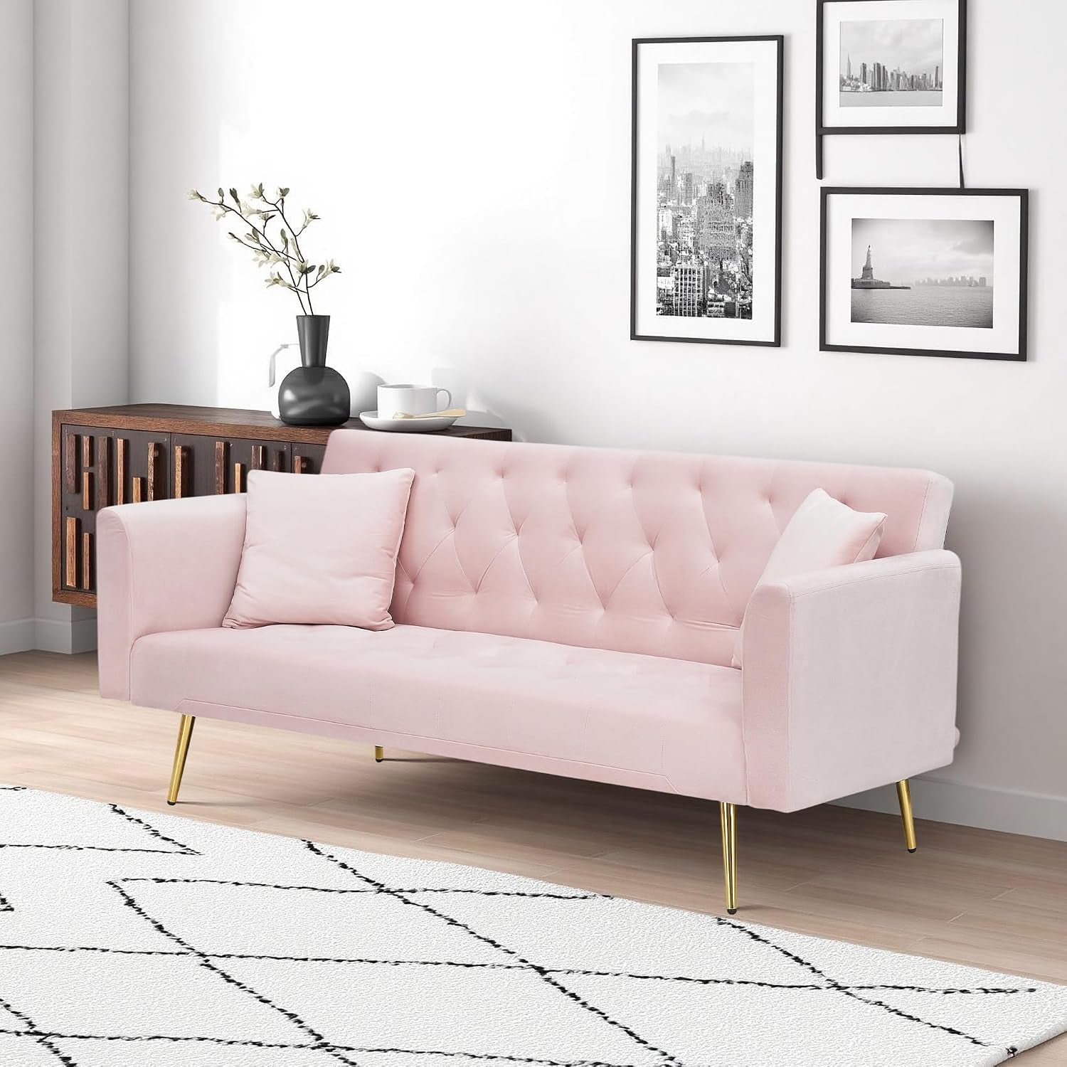 Light pink velvet futon sofa with tufted back and gold tapered legs, angled front view in living room