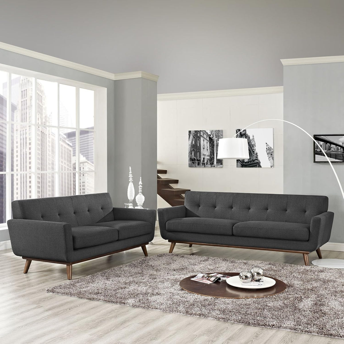 Grey upholstered sofa and loveseat in a bright living room with rug and floor lamp
