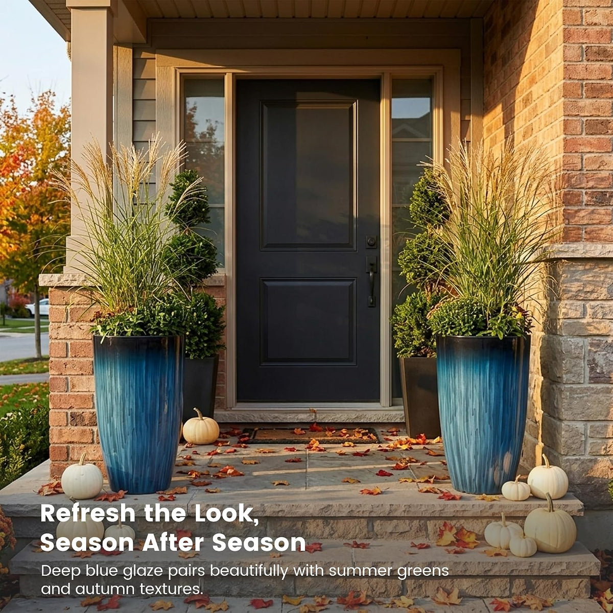 Two deep-blue glazed planters on a front stoop decorated with small white pumpkins and autumn leaves.