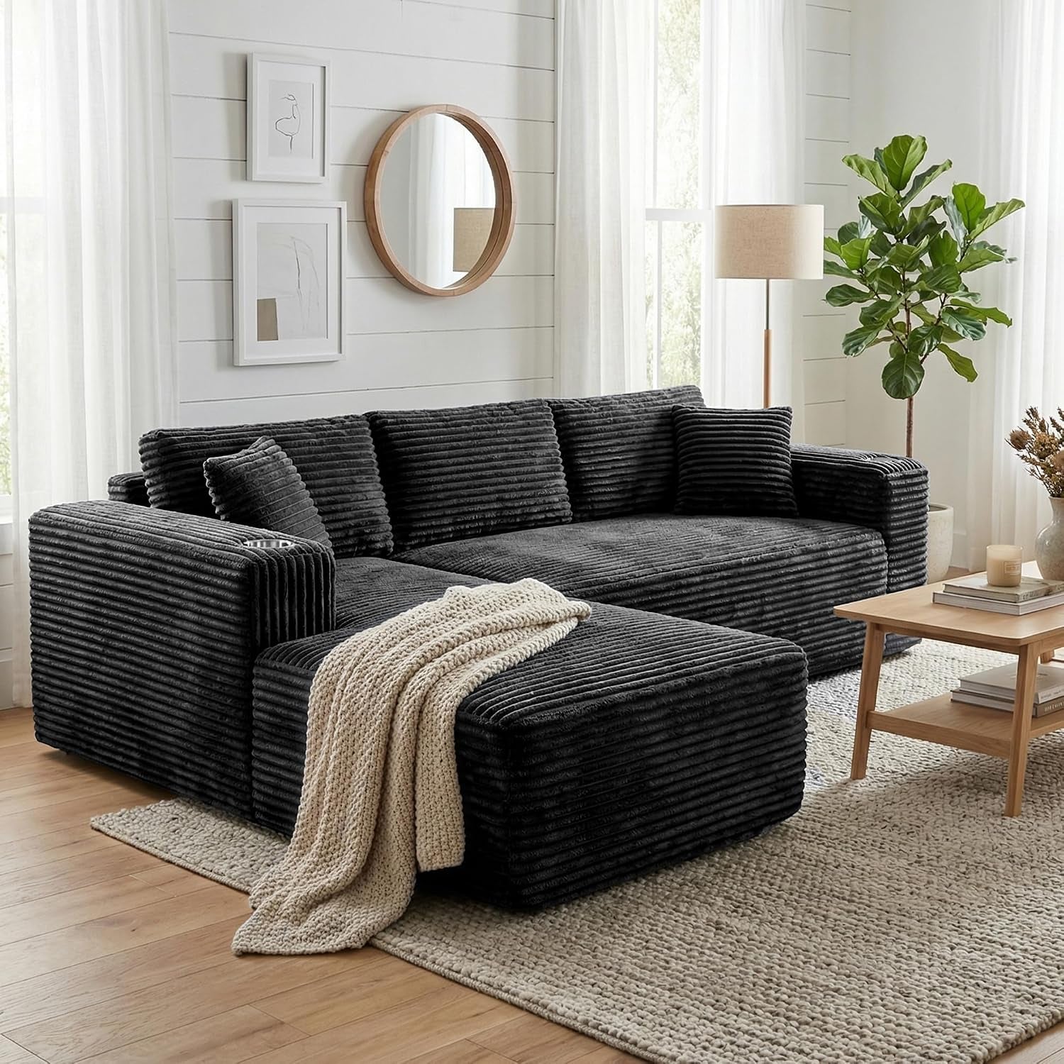Front-facing living room shot of the charcoal corduroy sectional with throw blanket on chaise.