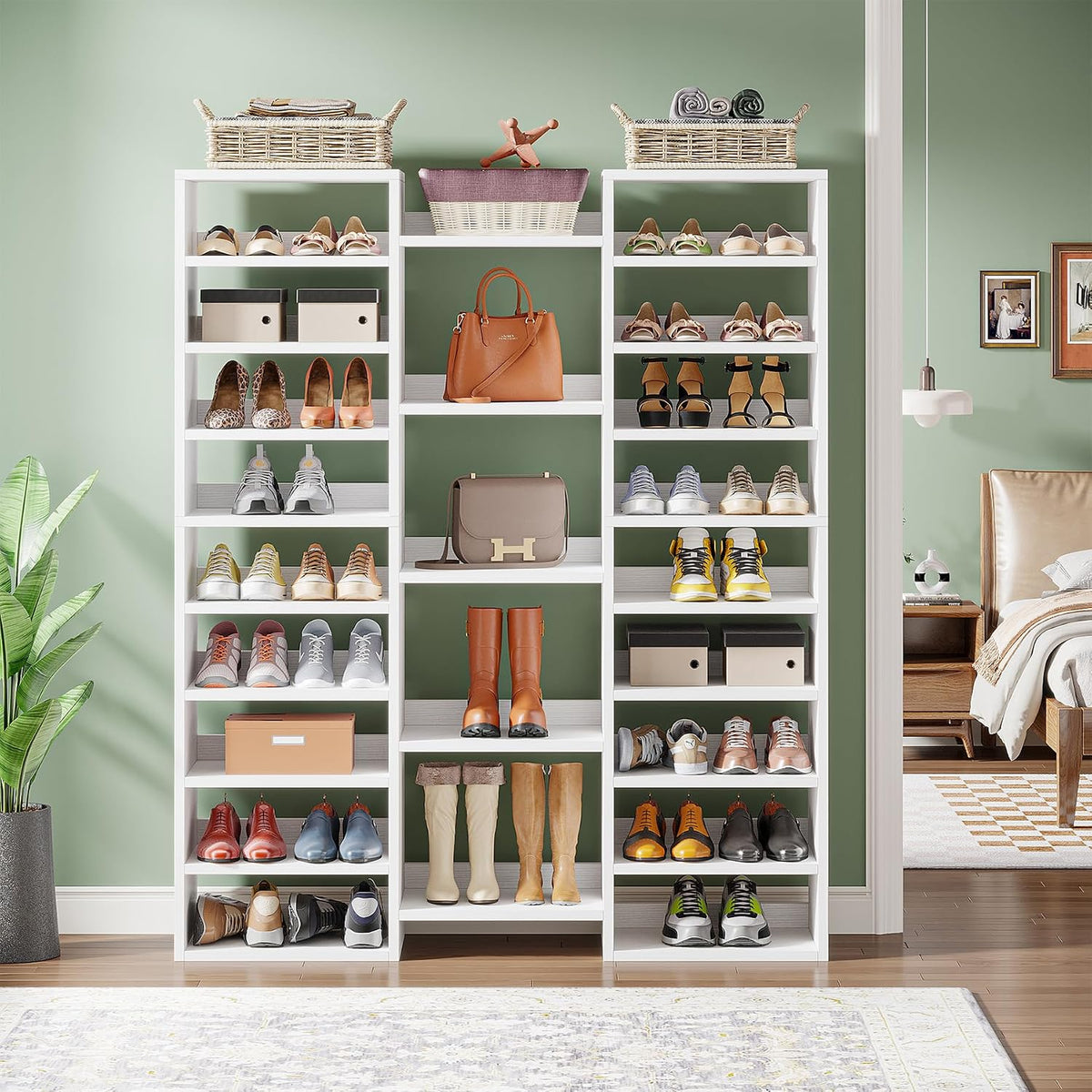 Front view of the white 14-tier shoe rack styled against a green wall with bags and boots on display