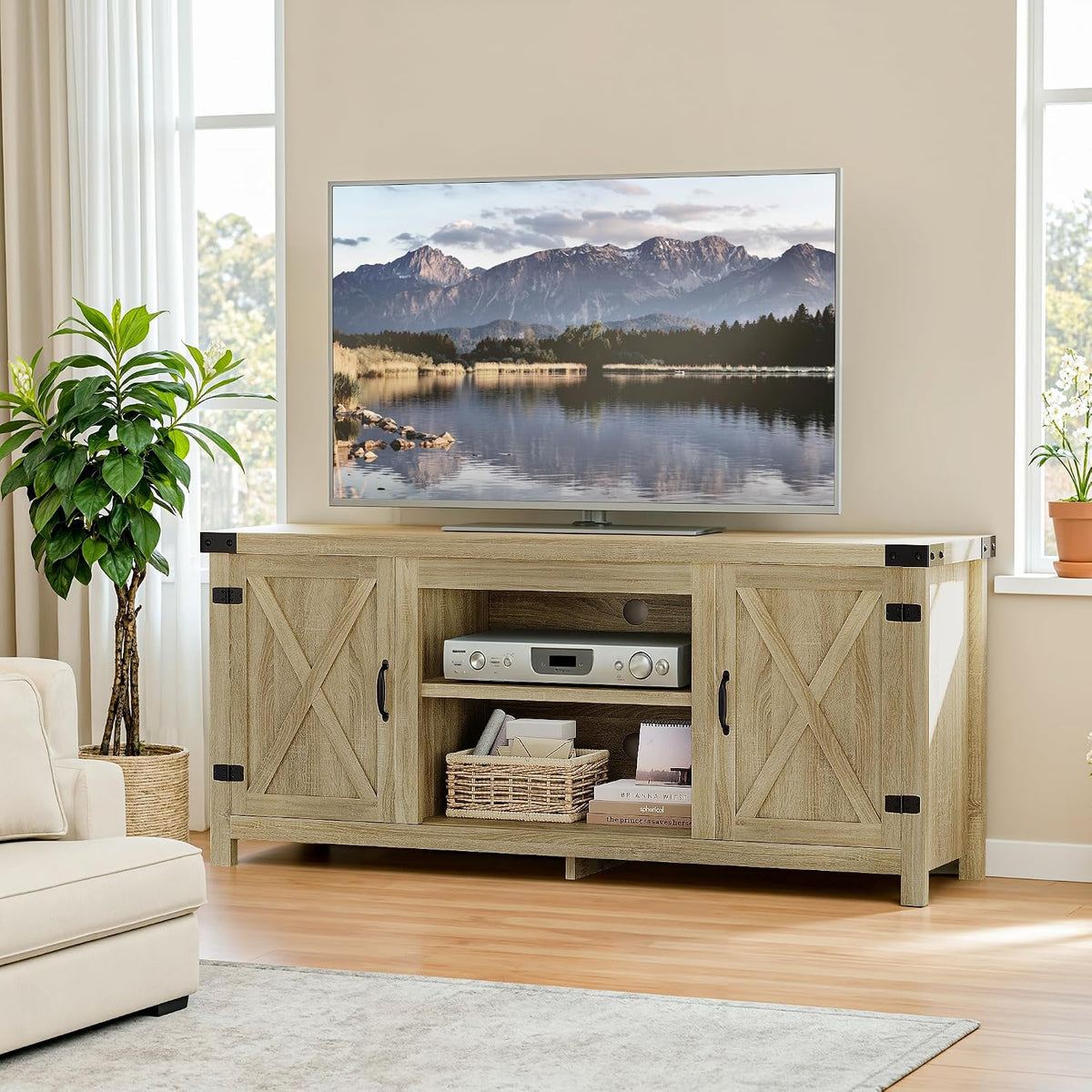 Wide living-room view of the light wood TV console beneath a large TV, flanked by plants and windows