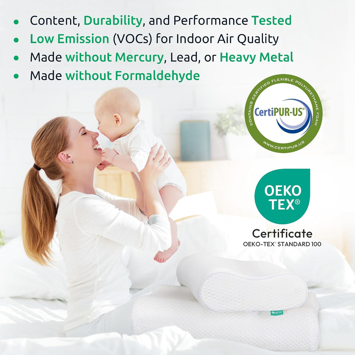 Mother lifting a baby on a bright bed with two white contoured pillows stacked nearby and certification logos visible