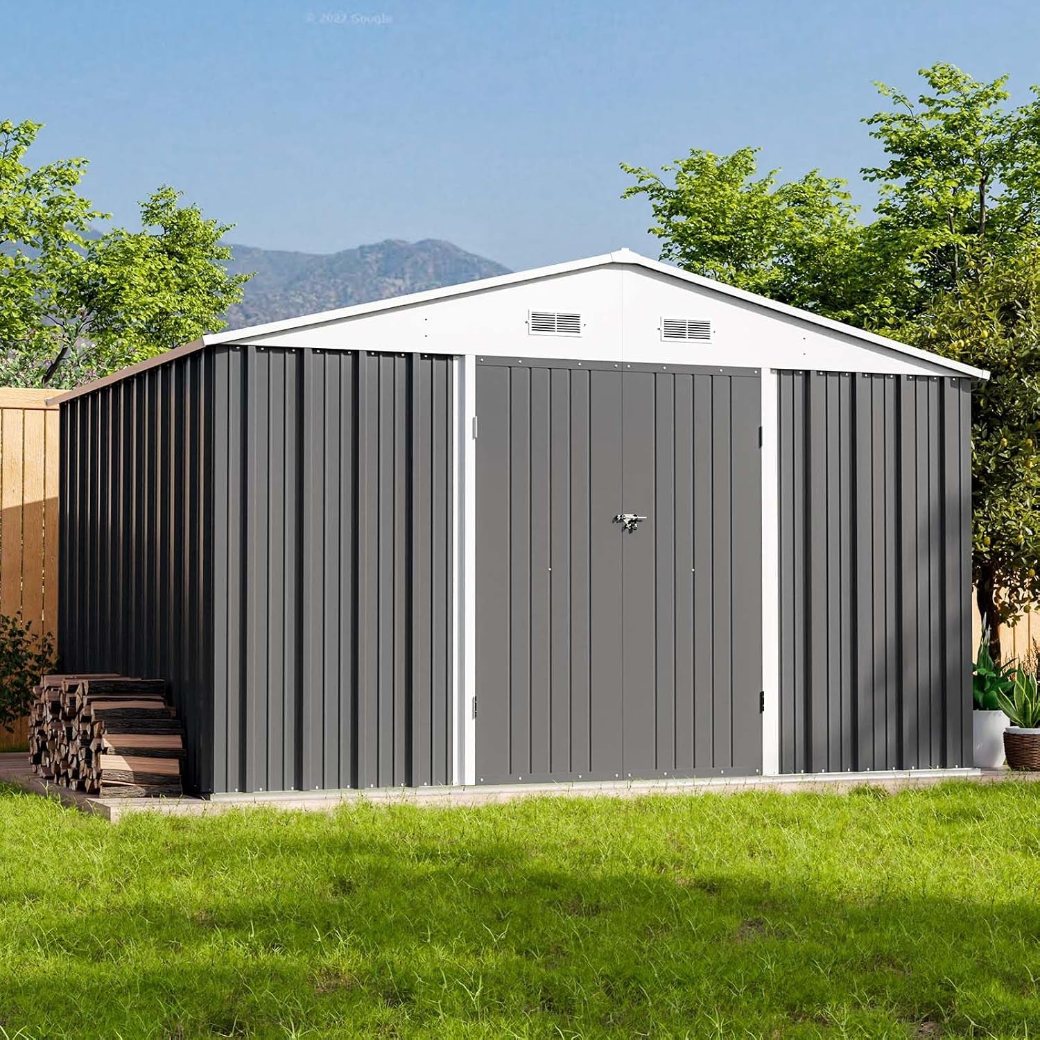 Front view of a dark gray metal shed with white gable and trim set on a concrete edge with stacked firewood nearby.