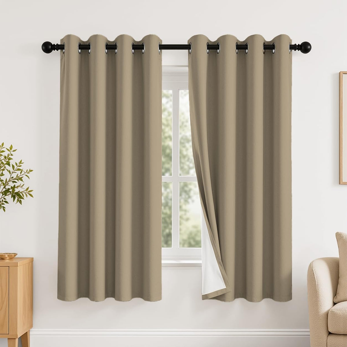 Window with two taupe grommet curtains hung on a black rod, one side slightly opened to reveal white backing.