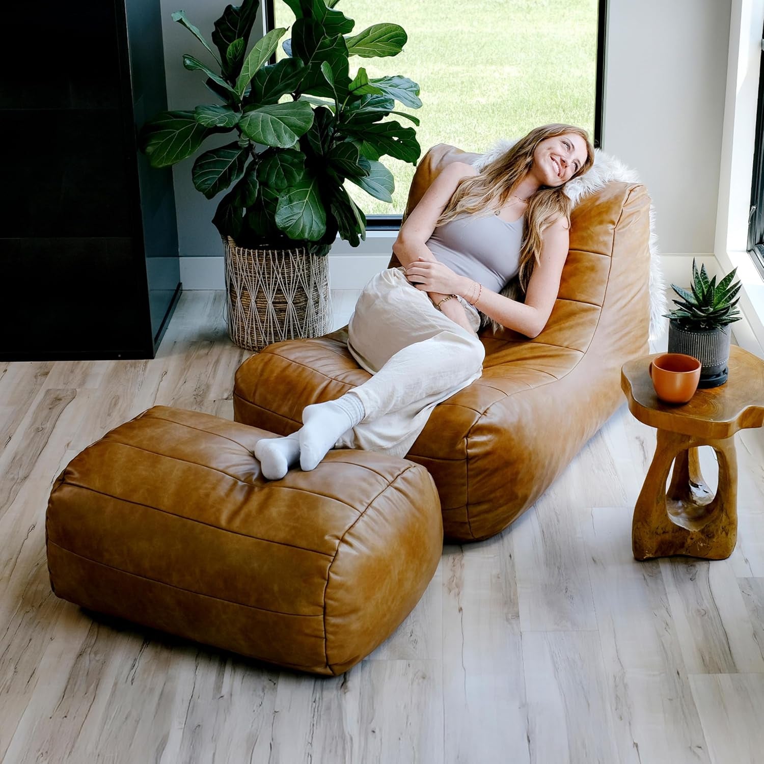 Caramel tan lounge chair and ottoman in room setting, top-right view with person reclining on the chair
