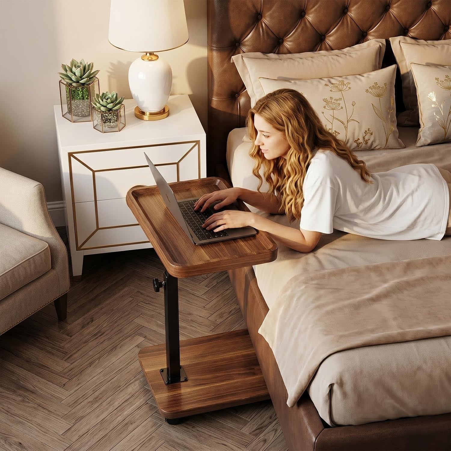 Woman reclining on a bed using an adjustable walnut C-shaped end table with a laptop.