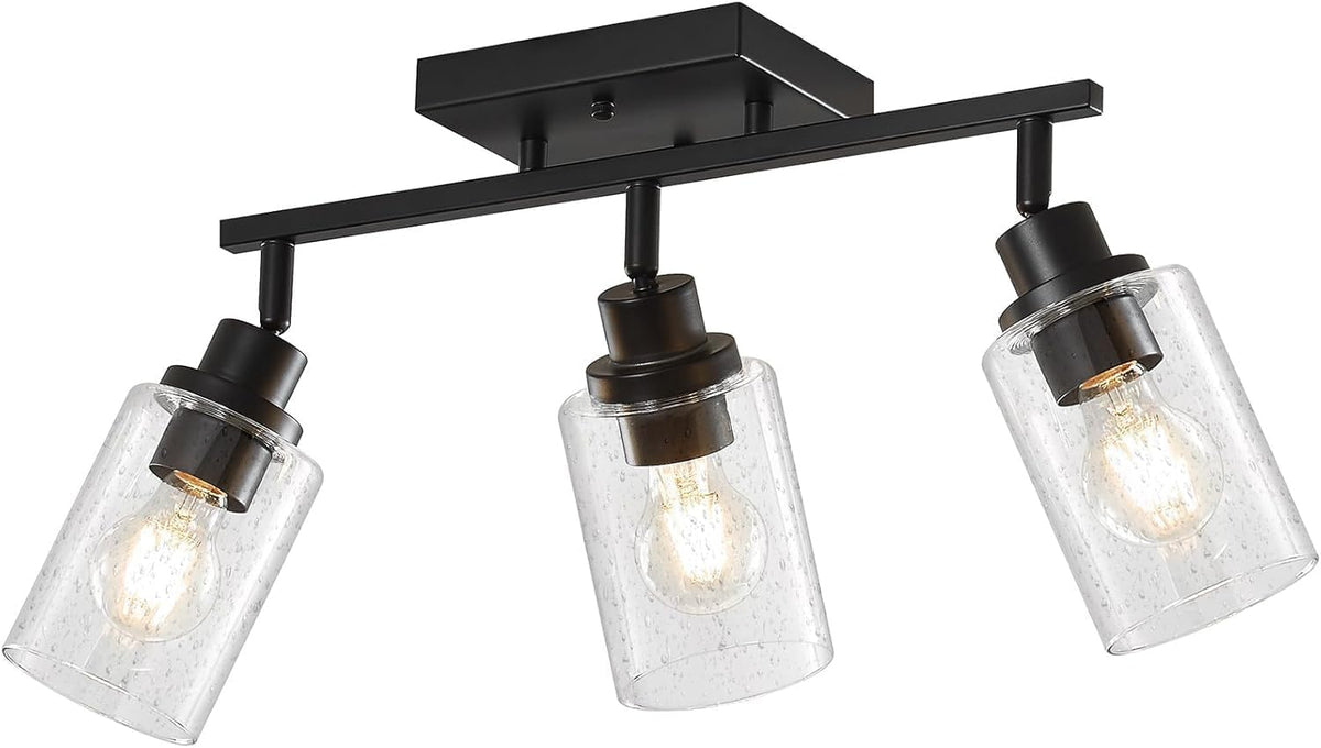 Angled close view of a three-light matte black bar showing hardware, posts and seeded glass shades