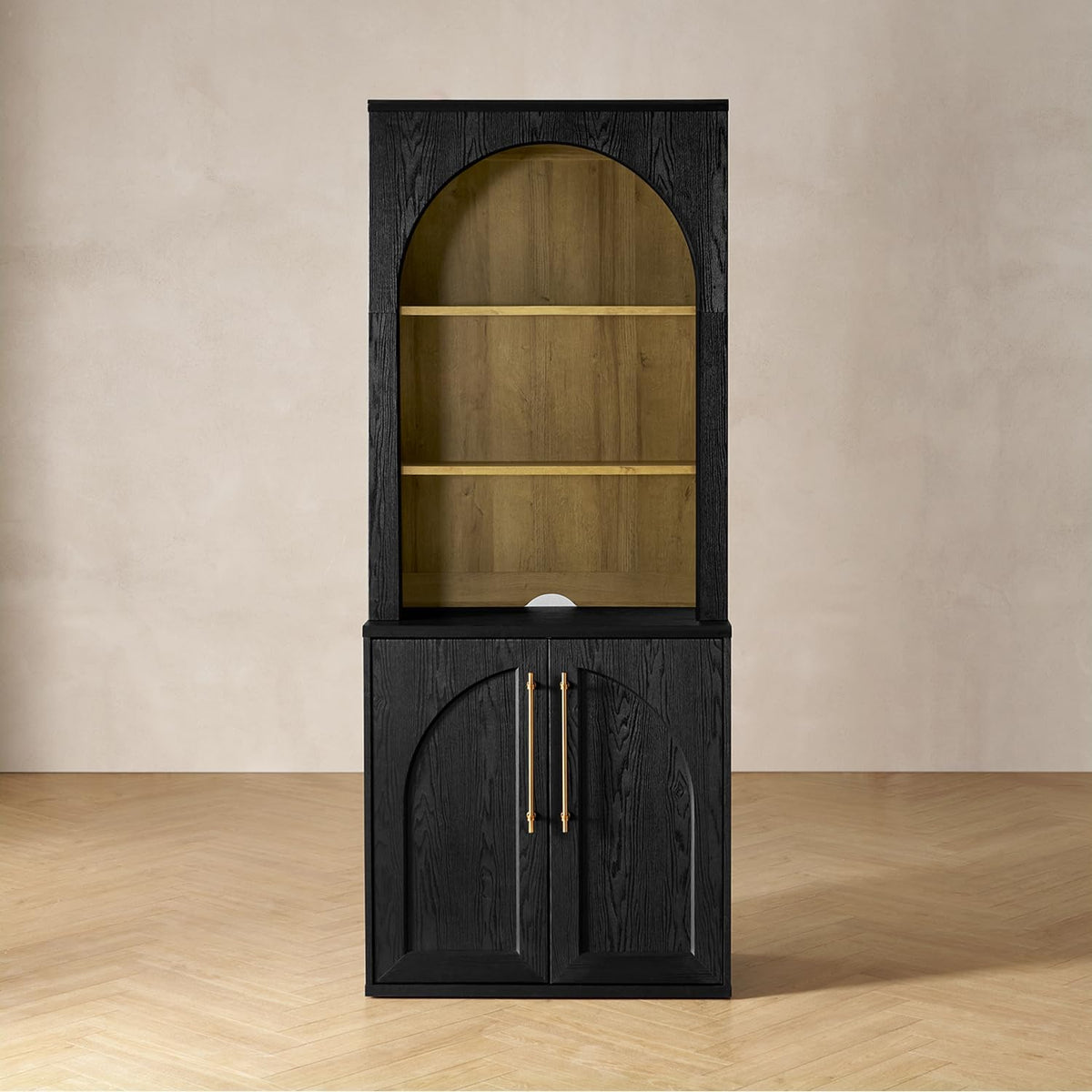 Black tall storage cabinet with arched hutch, two-door base with long gold vertical handles and warm wood interior shelves.