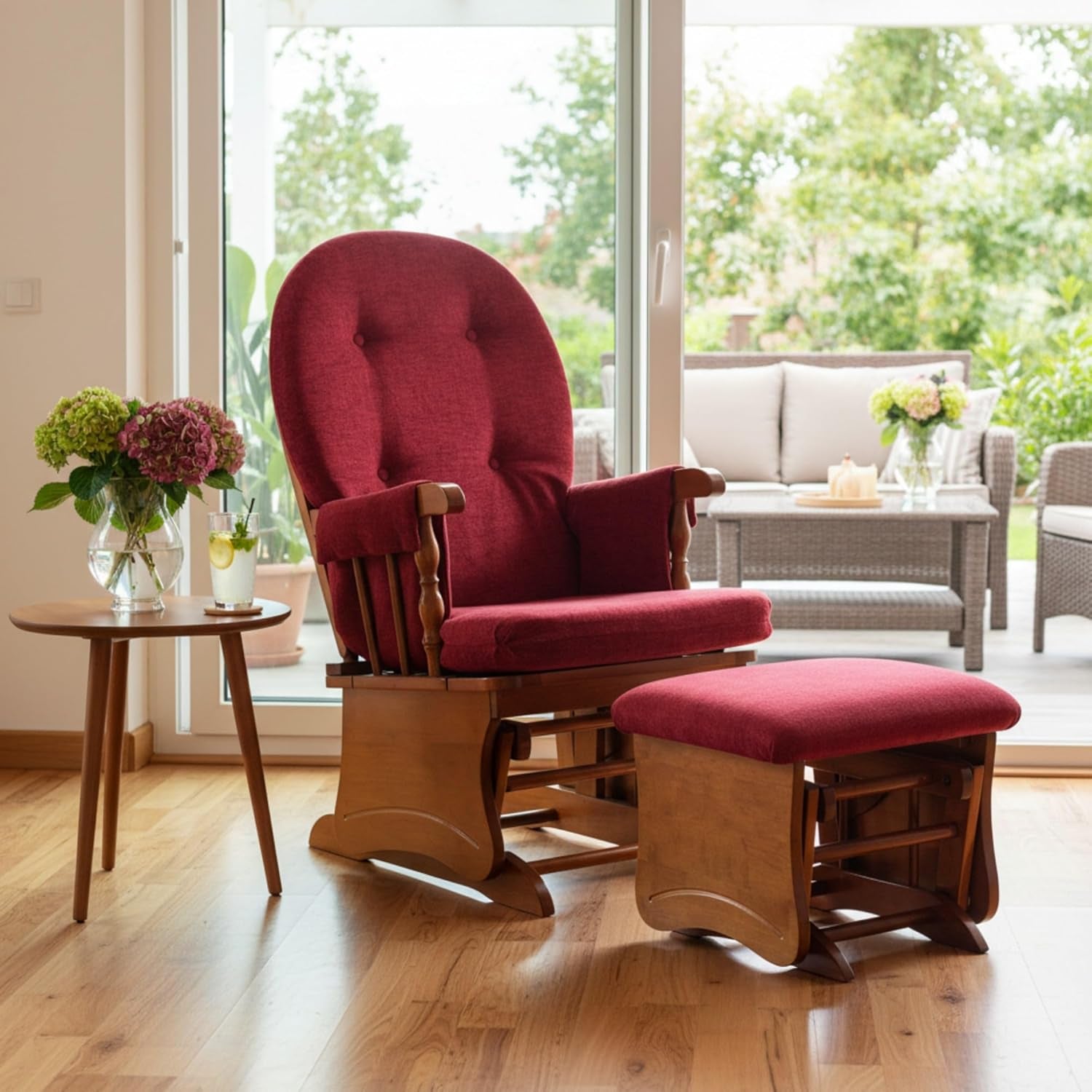 Three-quarter view of a red-upholstered glider chair with matching ottoman on an oak-finish wooden base in a sunlit room.