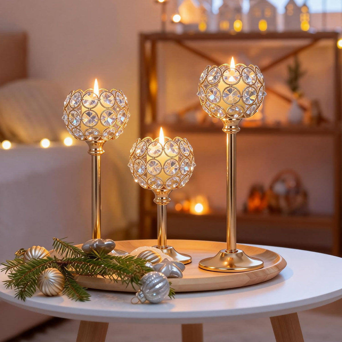 Three gold crystal tealight holders lit on a wooden tray atop a small white table in a cozy living room.