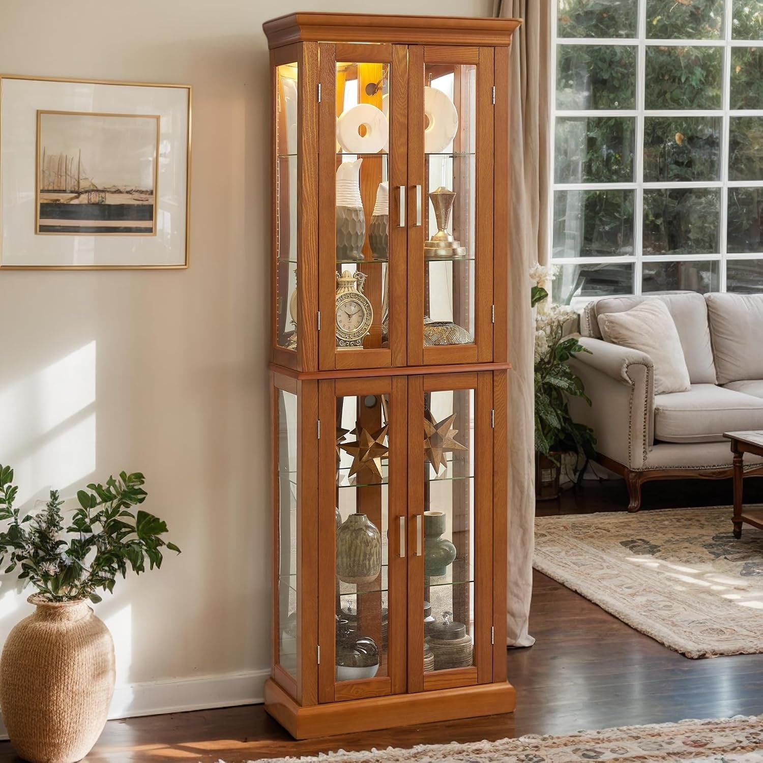 Tall two-section oak curio cabinet beside a sofa in a sunlit living room with decorative items inside.