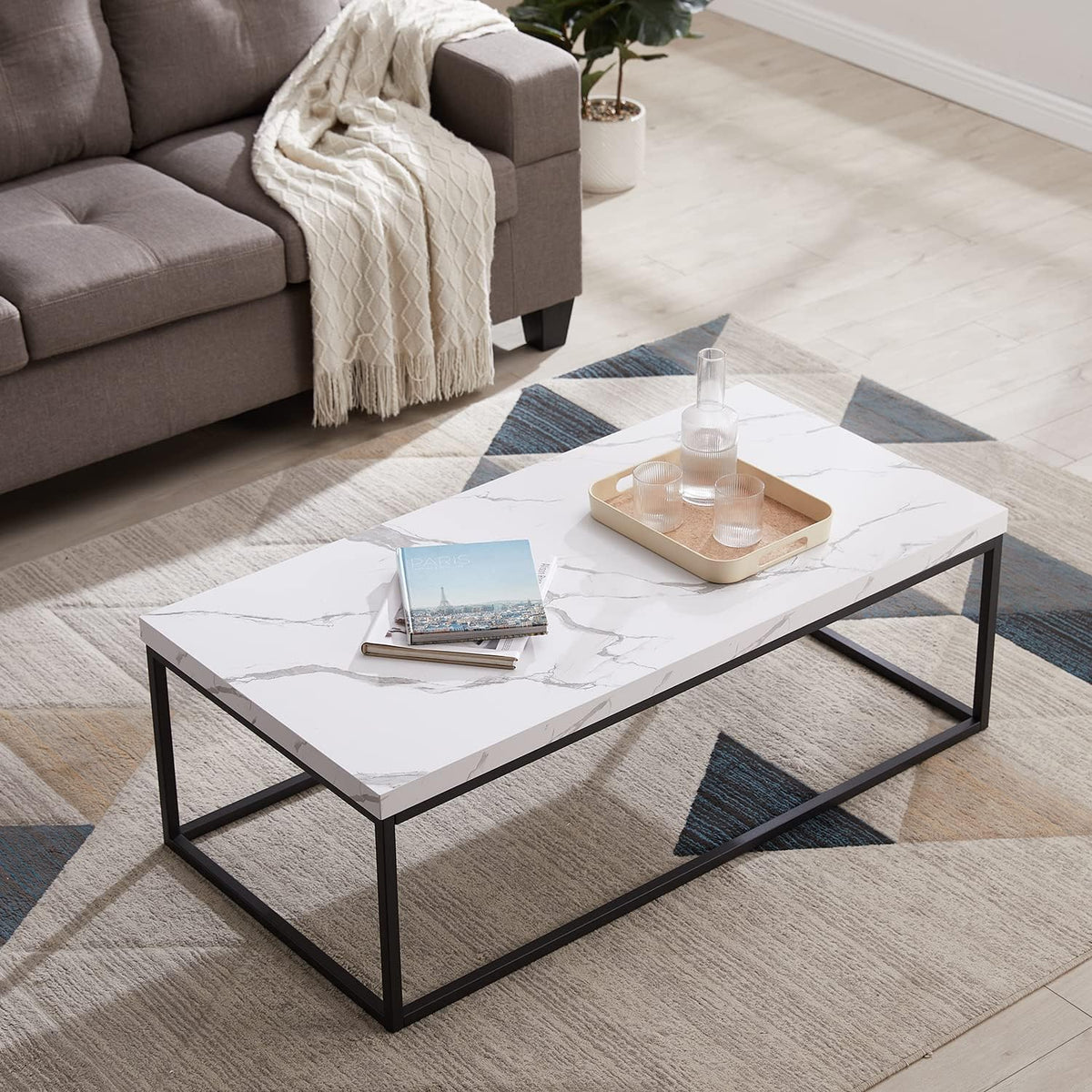White marble-laminated rectangular coffee table with black metal frame angled front view in a living room