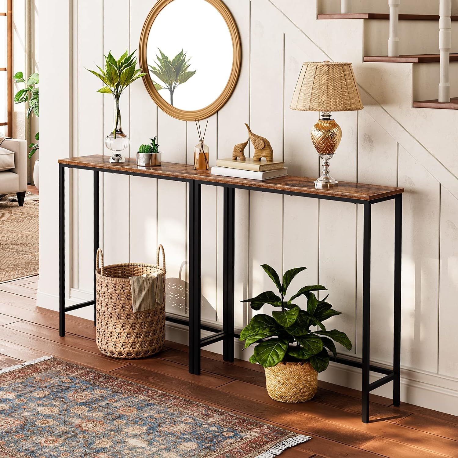 Rustic narrow console table styled in an entryway with lamp, plants, and mirror on top