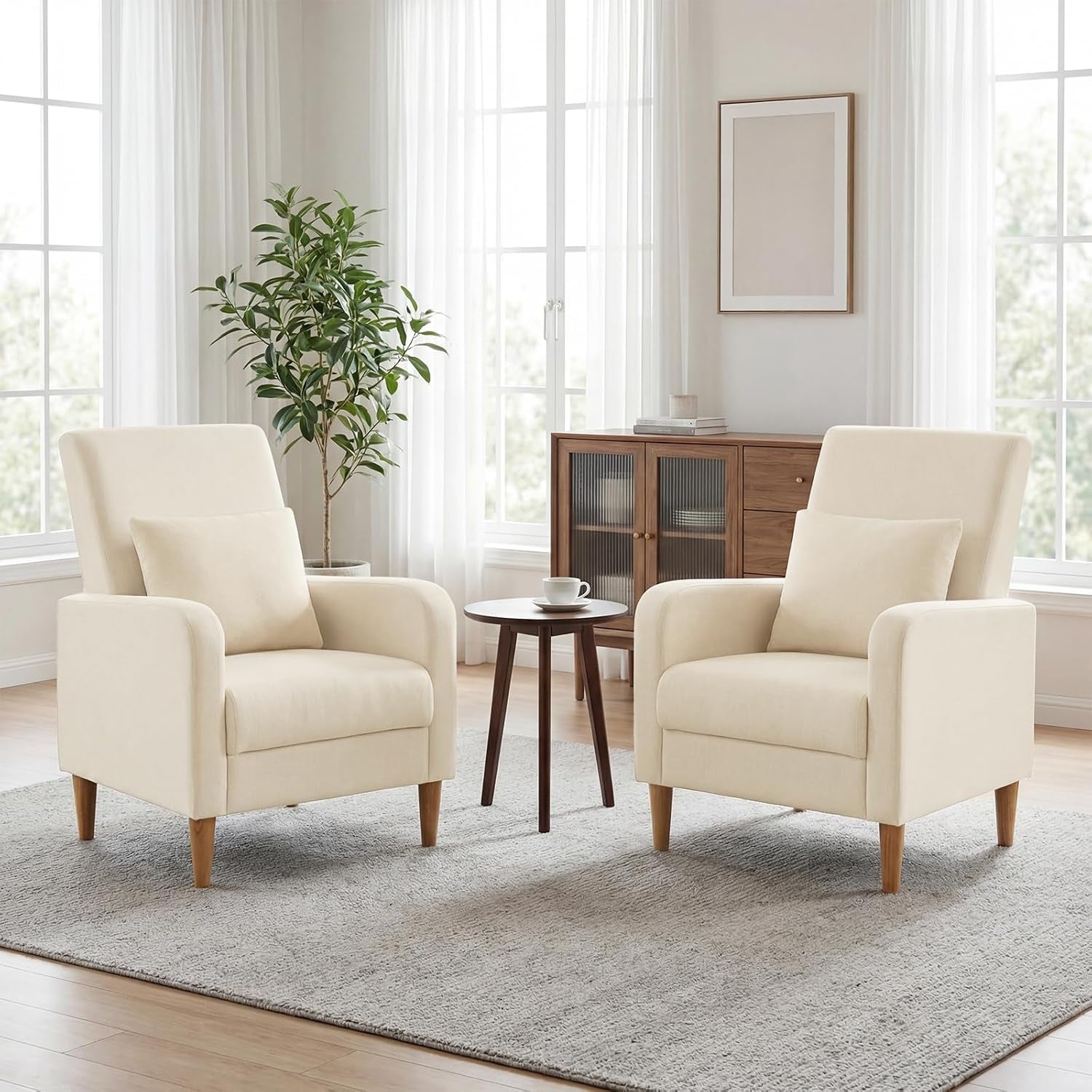 Two beige upholstered accent chairs paired in a bright living room beside a small round table