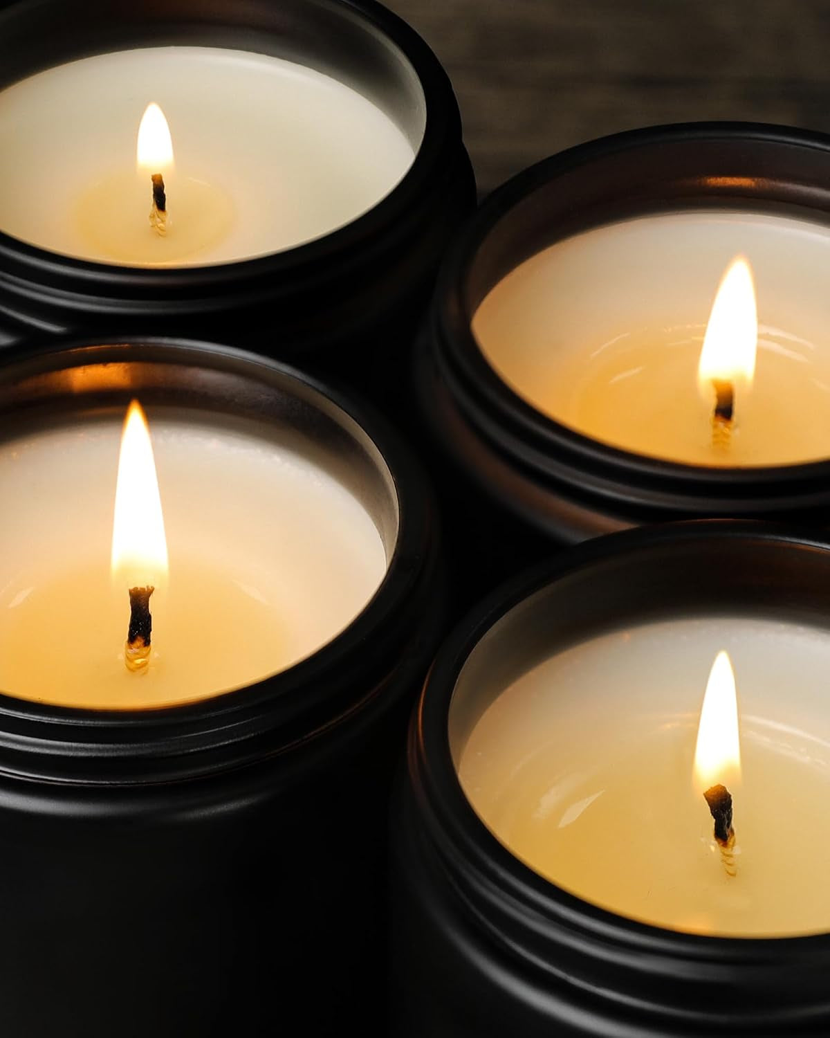 Close-up overhead of black jar candle interiors showing cream soy wax and lit wicks