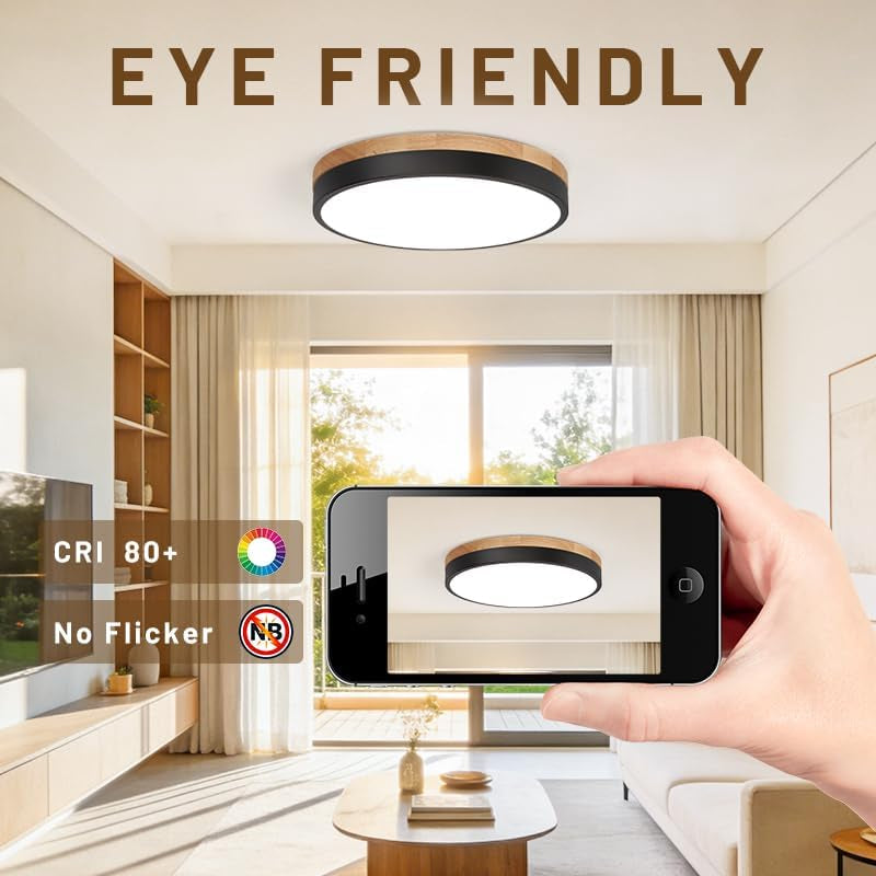 Hand holding a smartphone photographing the illuminated ceiling light in a bright living room.
