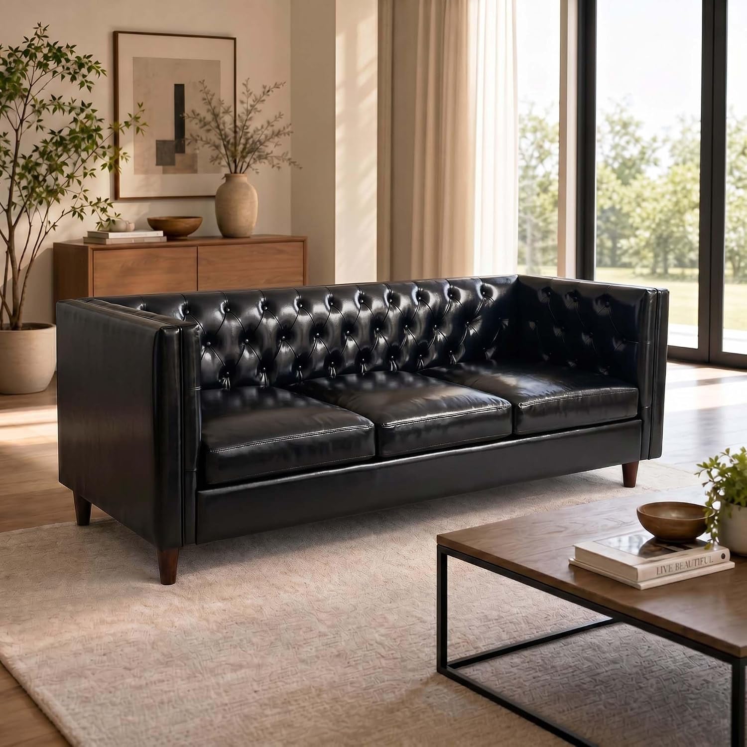 Black button-tufted three-seat sofa angled in a sunlit living room by large windows.