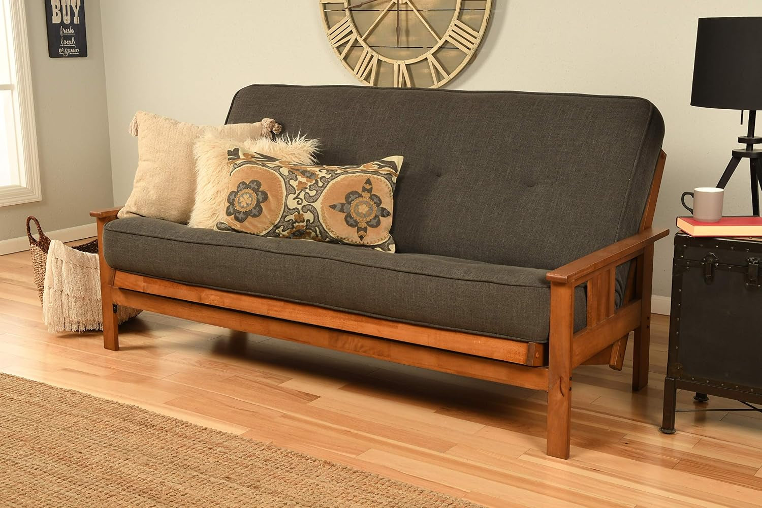 Full-size futon with charcoal cushion and medium wood Mission-style frame angled front view in a living room