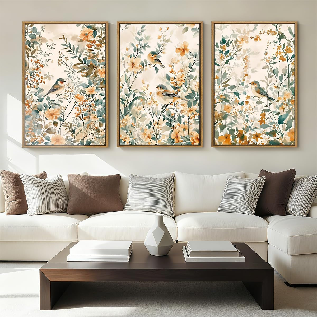 White sofa and dark wood coffee table beneath three framed botanical prints featuring birds and flowers.