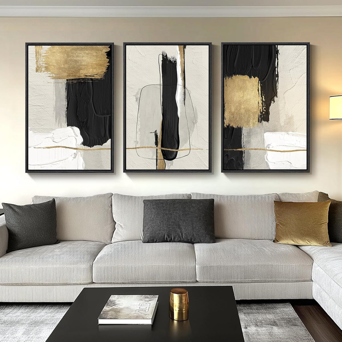 Three framed abstract panels with black and gold accents hung above a beige sectional sofa and black coffee table.