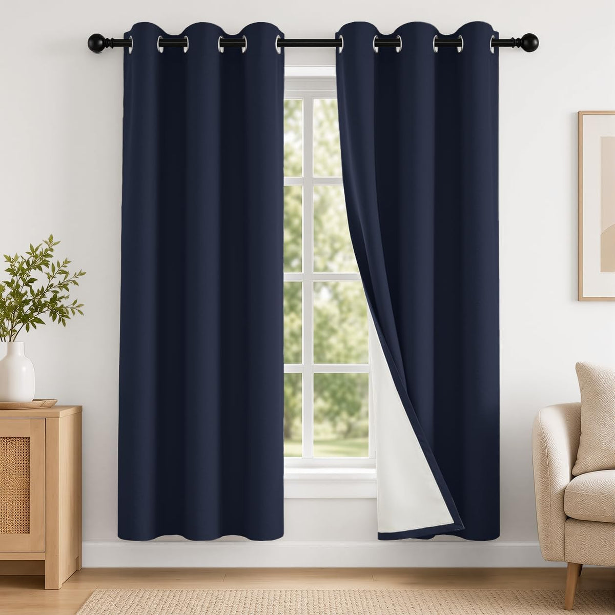 Navy grommet-top curtains framing a window, one panel folded to reveal white insulated backing.