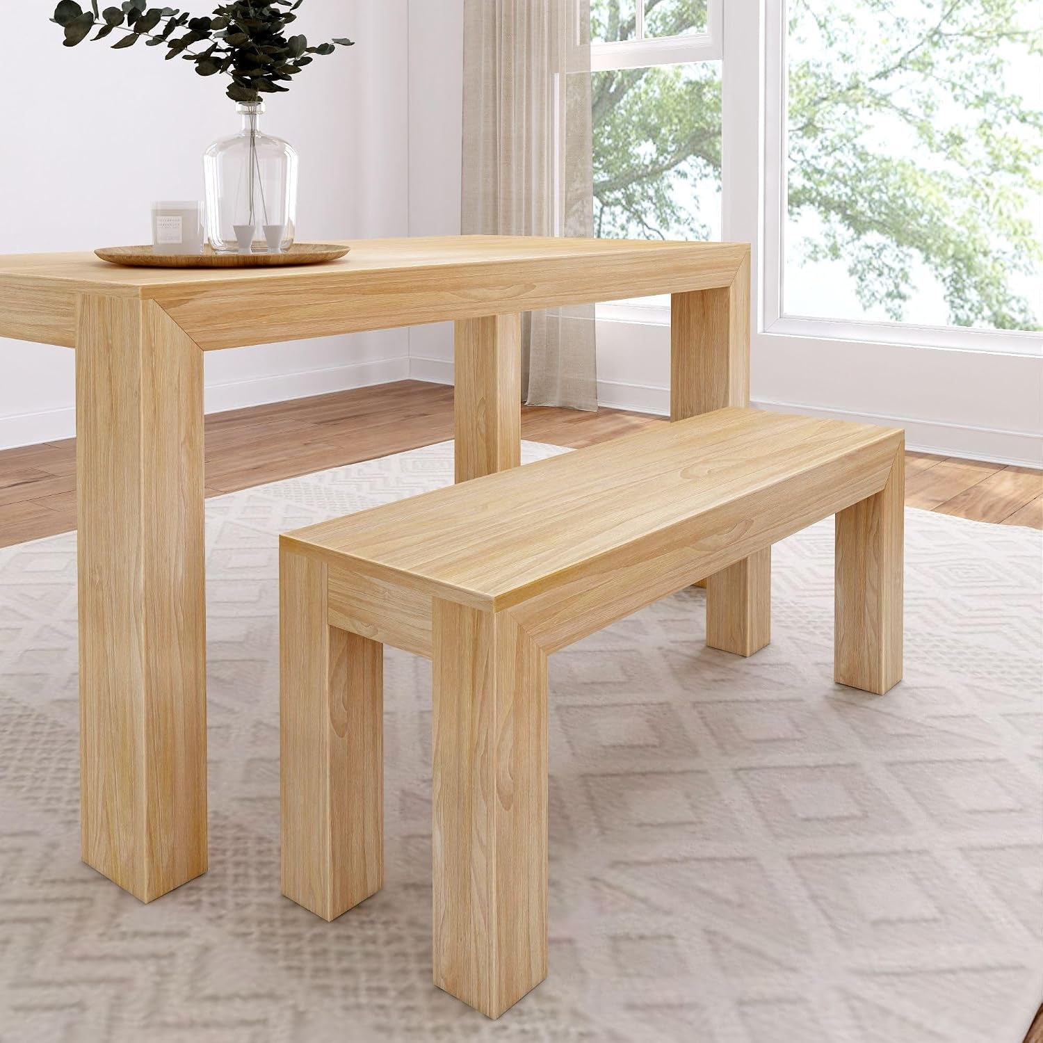 Full view of a solid pine dining table with matching bench in a light natural finish beside a window.