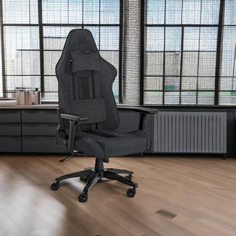 Gray fabric gaming chair placed in a loft-style office with large industrial windows.