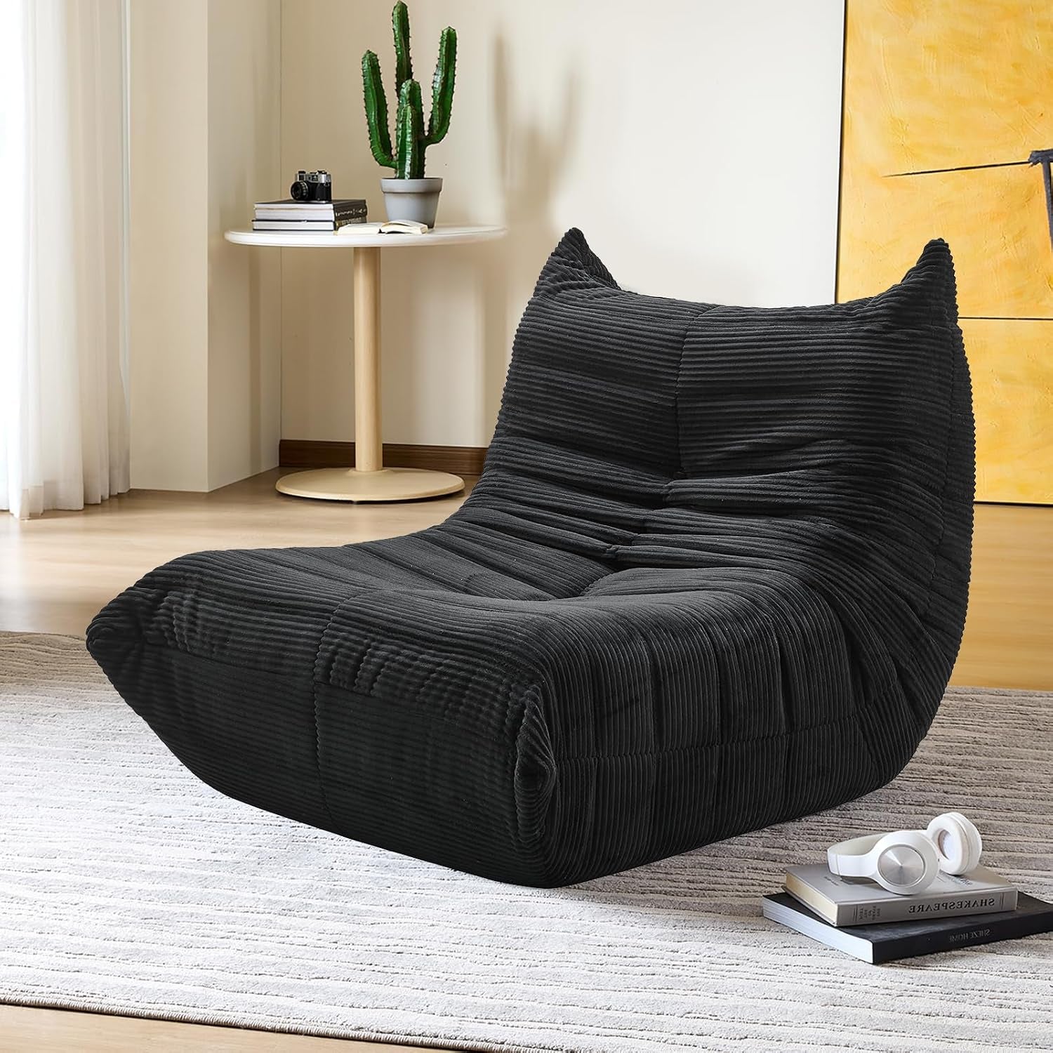 Charcoal ribbed lounge chair on a striped rug with stacked books and white headphones at the front