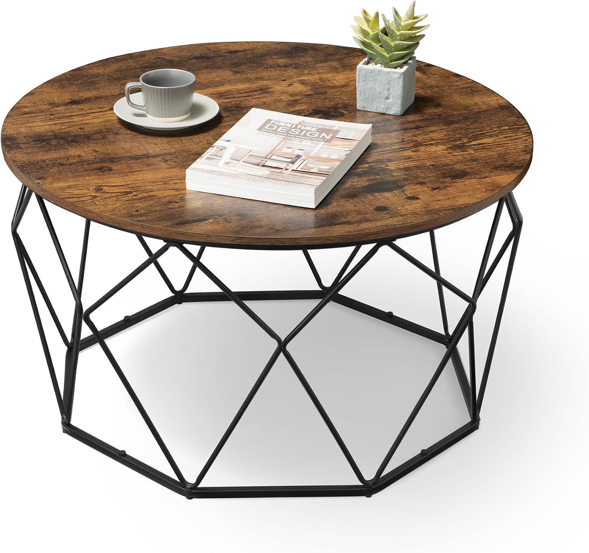 Round honey-brown wood-look coffee table top with a geometric black metal base, styled with a cup on a saucer, a book, and a
