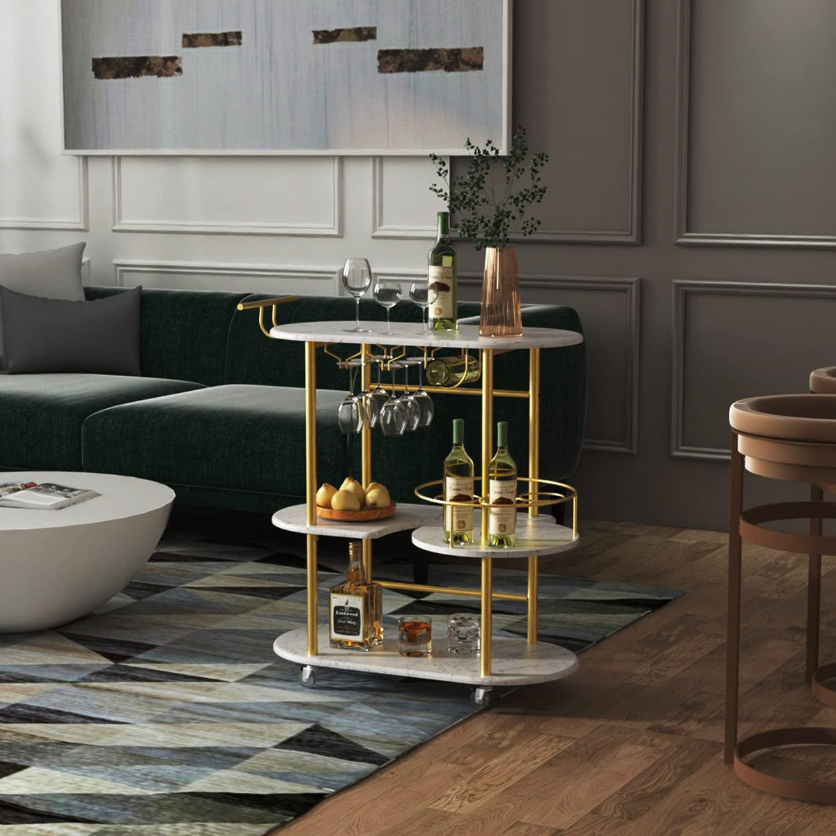Gold-framed bar cart with white marble shelves beside a green sofa on a patterned rug