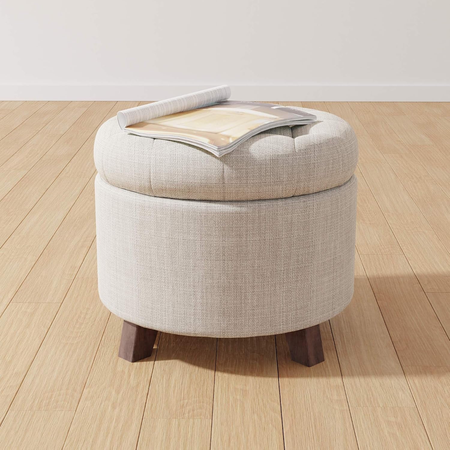 Angled view of beige ottoman with a magazine on top on light wood flooring