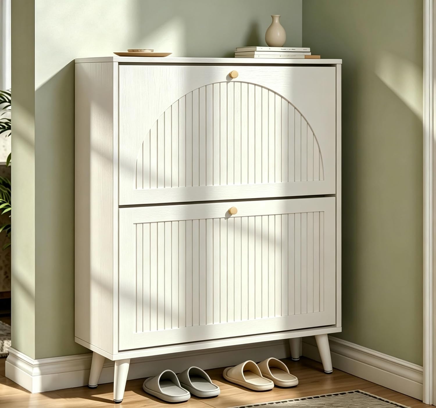 White shoe cabinet shown in a corner with two fluted drawer fronts and tapered legs