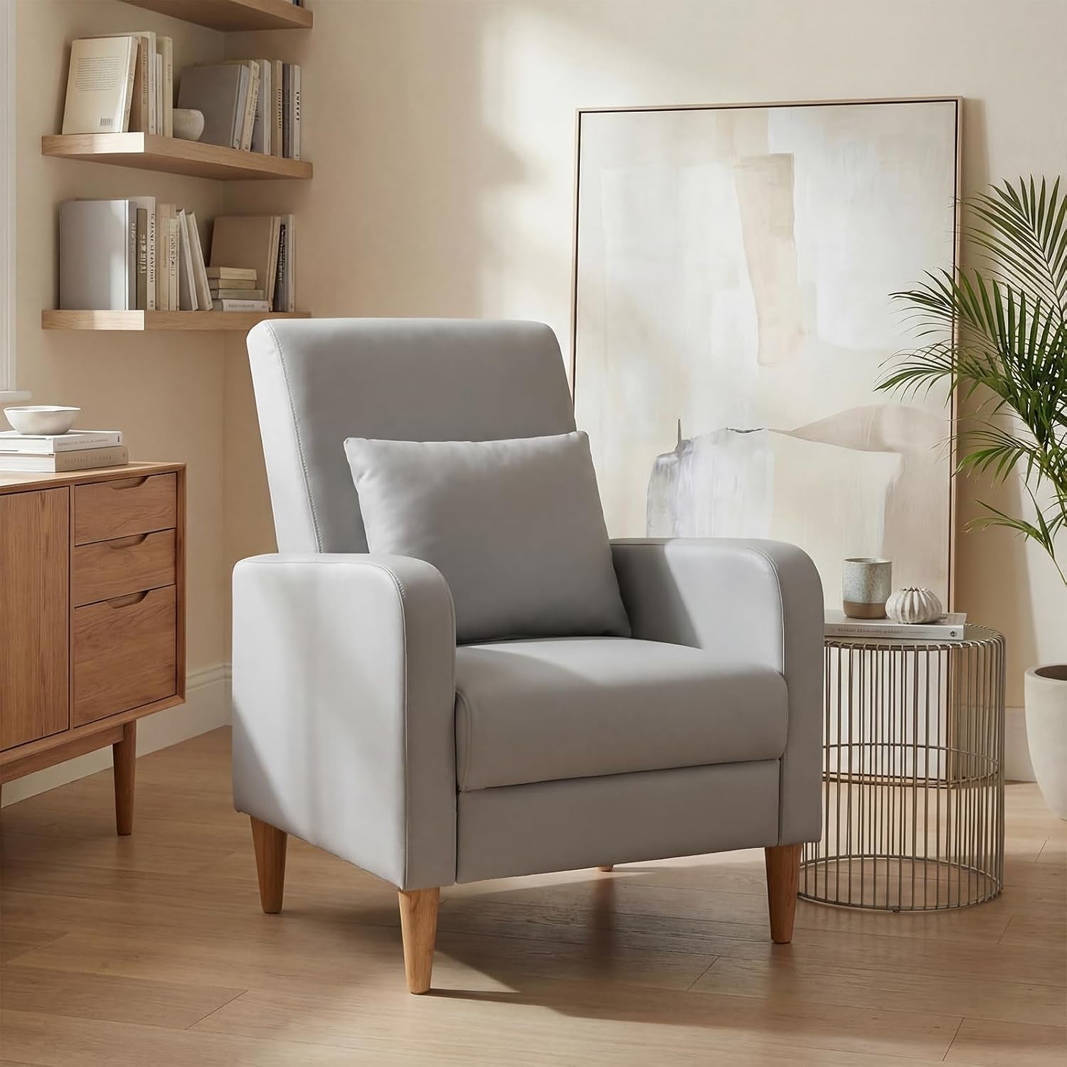 Single beige upholstered accent chair with wood legs beside a wire side table and artwork