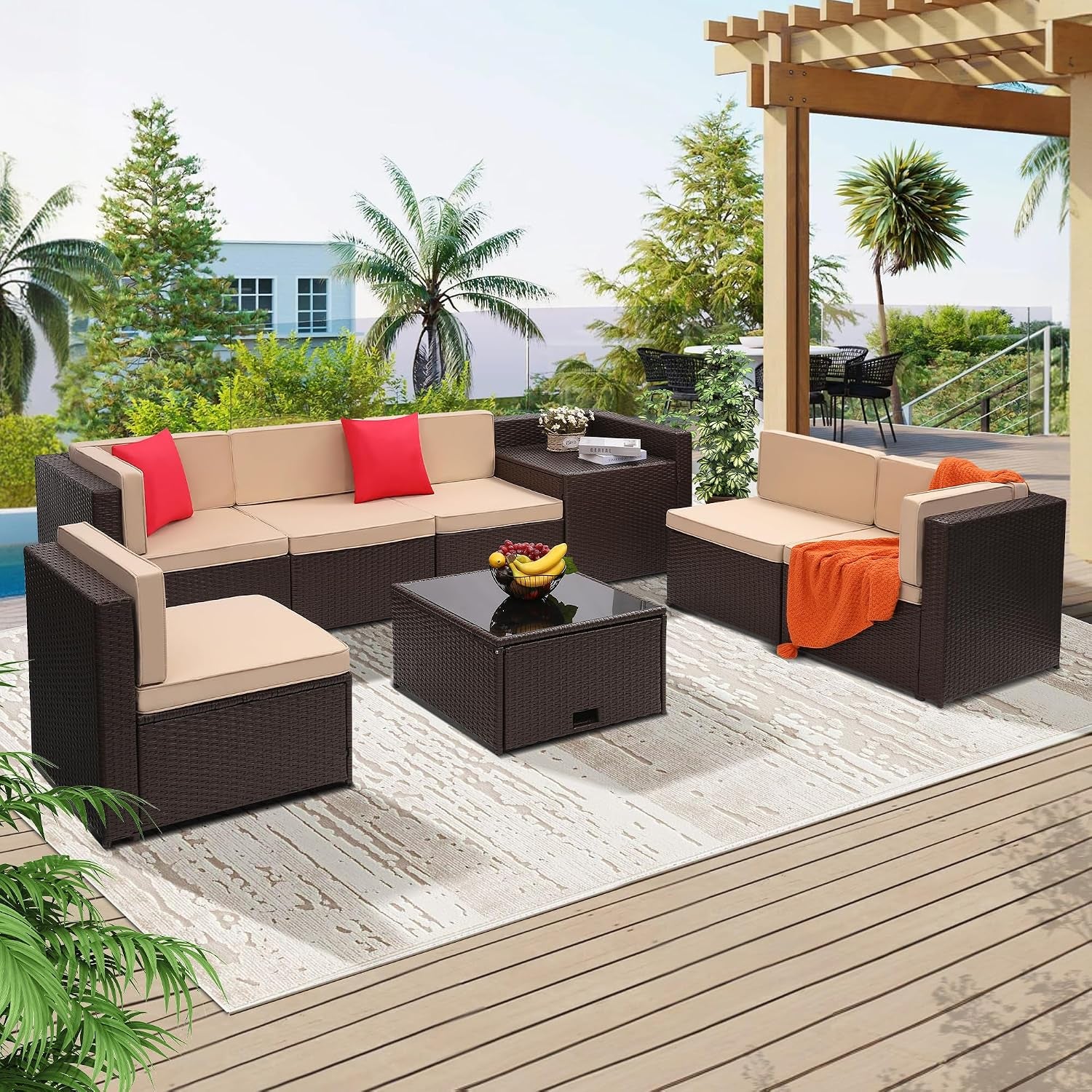 Beige-cushioned rattan patio set on a deck under a pergola with tropical plants in the background.