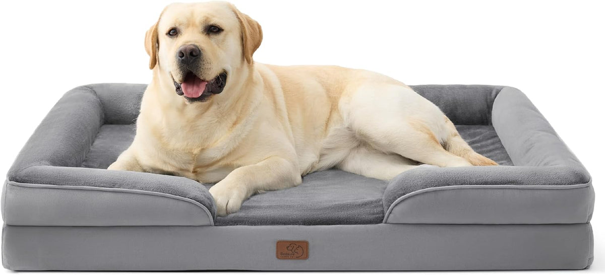 Large yellow lab reclined in a charcoal gray rectangular bolstered dog bed shown from the front